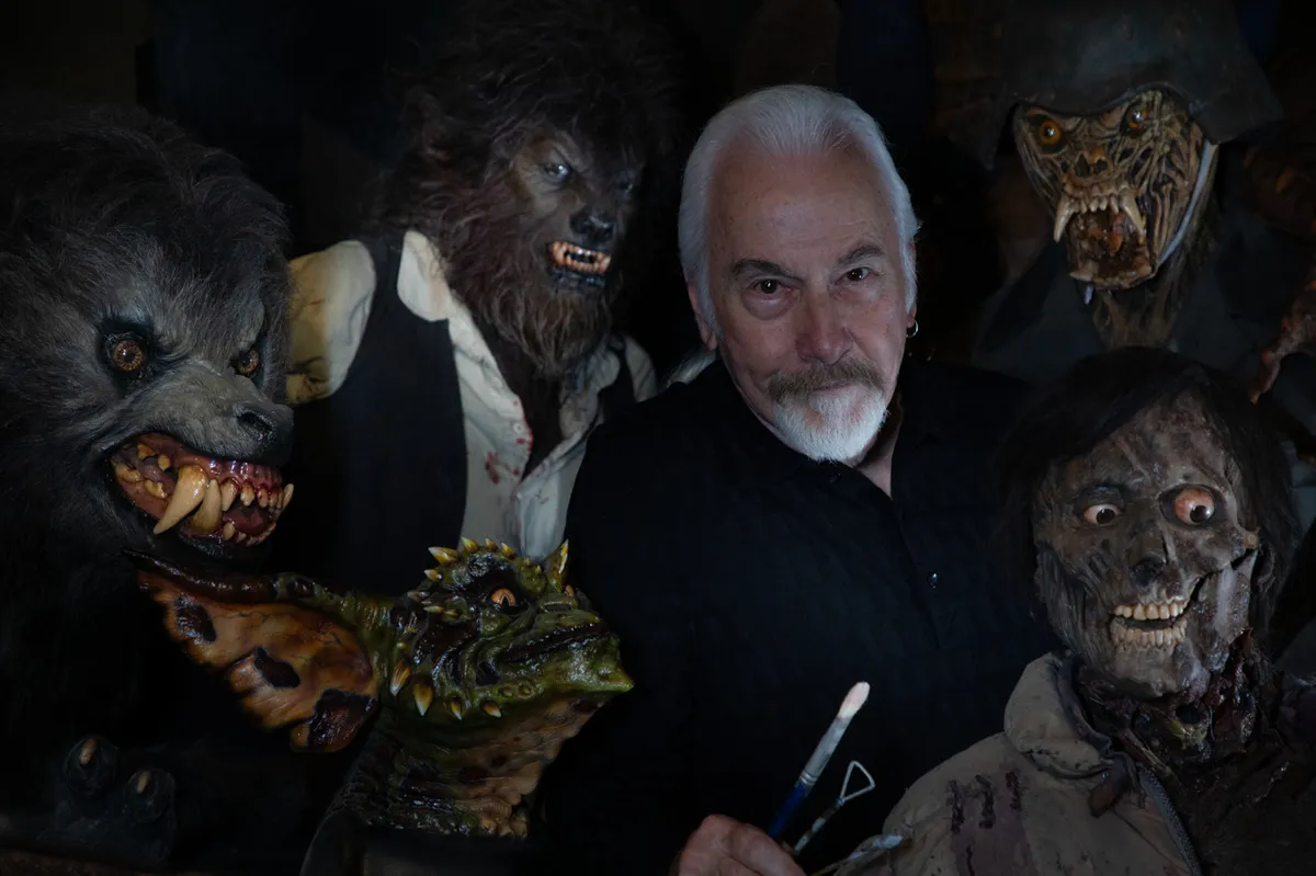 Legendary make-up artist Rick Baker, looking thoughtful, likely surrounded by his creative work.