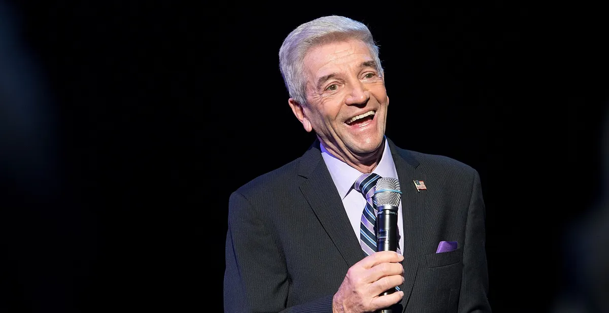 A black and white portrait of comedian Tom Dreesen smiling