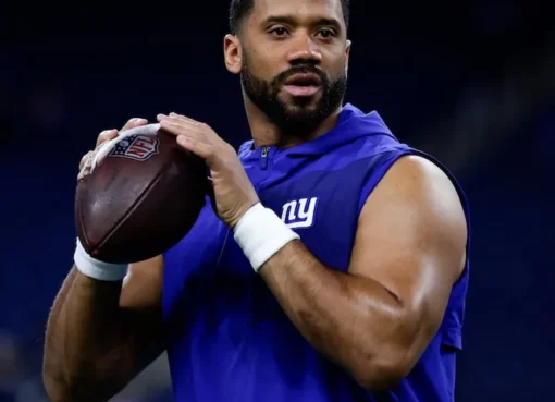 Russell Wilson in a suit, smiling.
