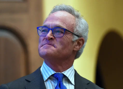 Scott Pelley speaking into a microphone on a news set.
