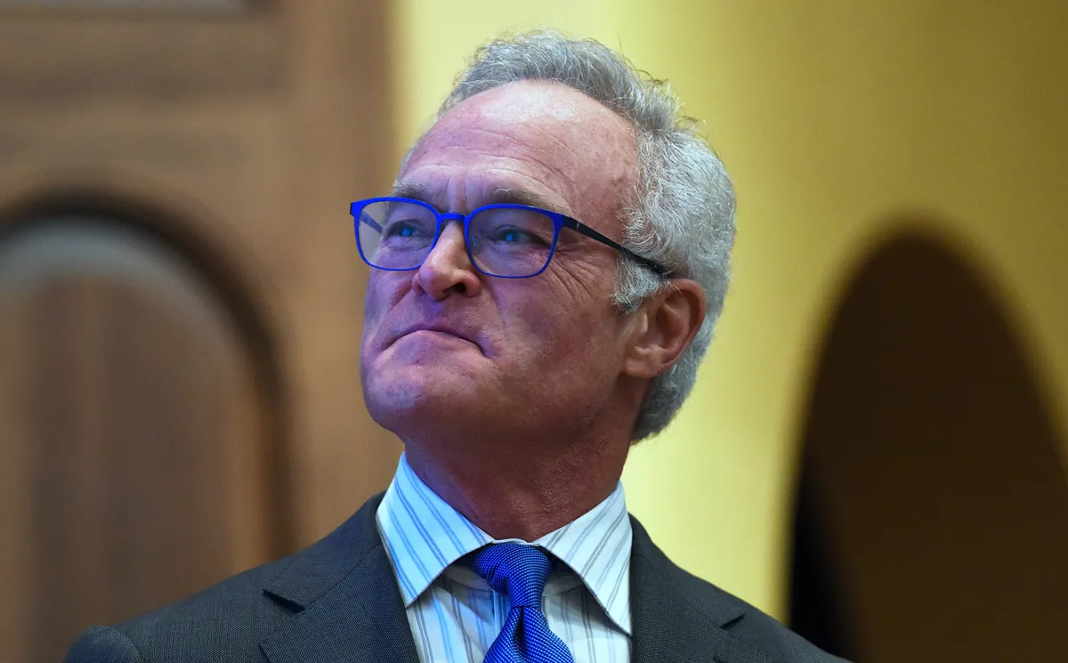 Scott Pelley speaking into a microphone on a news set.