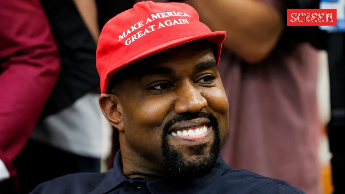 Kanye West standing on a stage with a moody spotlight