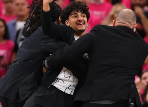 Fans running onto a basketball court during an NBA game.