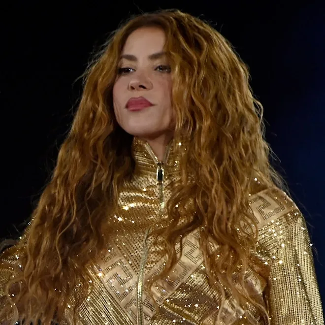 Shakira performing on stage with vibrant lighting.