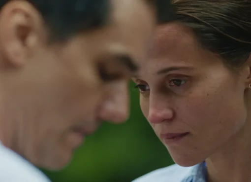 Alicia Vikander looking thoughtfully in a scene from 'The Last Day,' bathed in soft, elegant light.