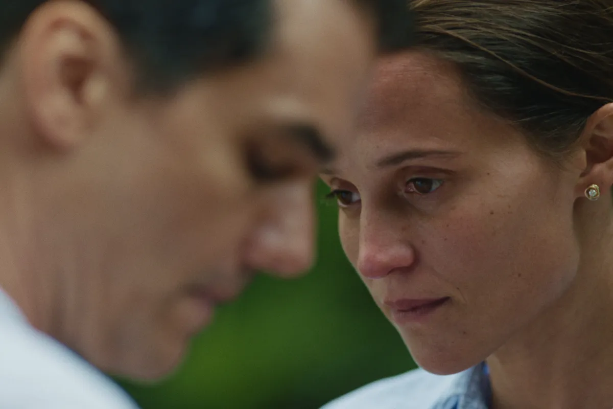 Alicia Vikander looking thoughtfully in a scene from 'The Last Day,' bathed in soft, elegant light.