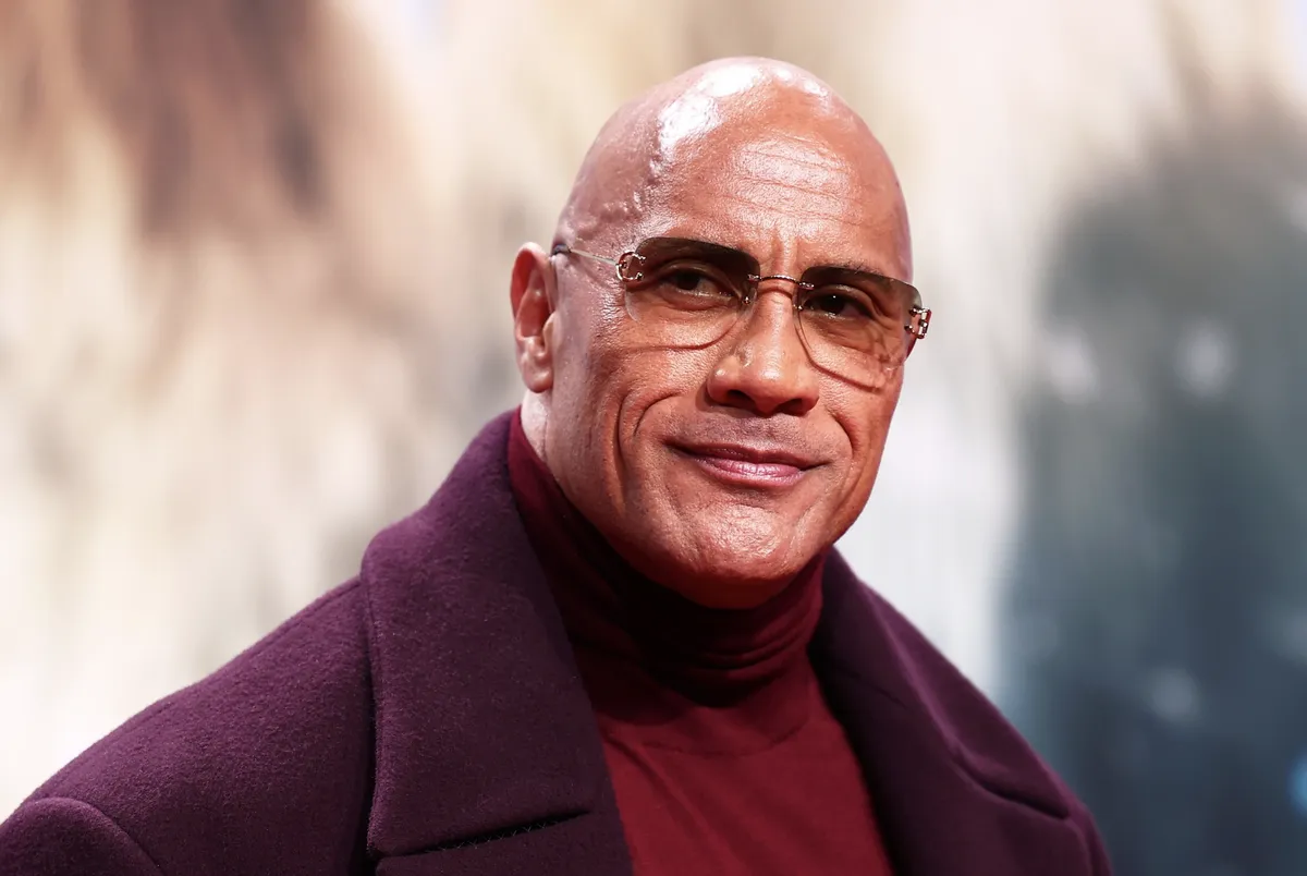 Dwayne 'The Rock' Johnson looking thoughtful and serious, with a blurred, slightly dramatic blue and red visual style in the background.