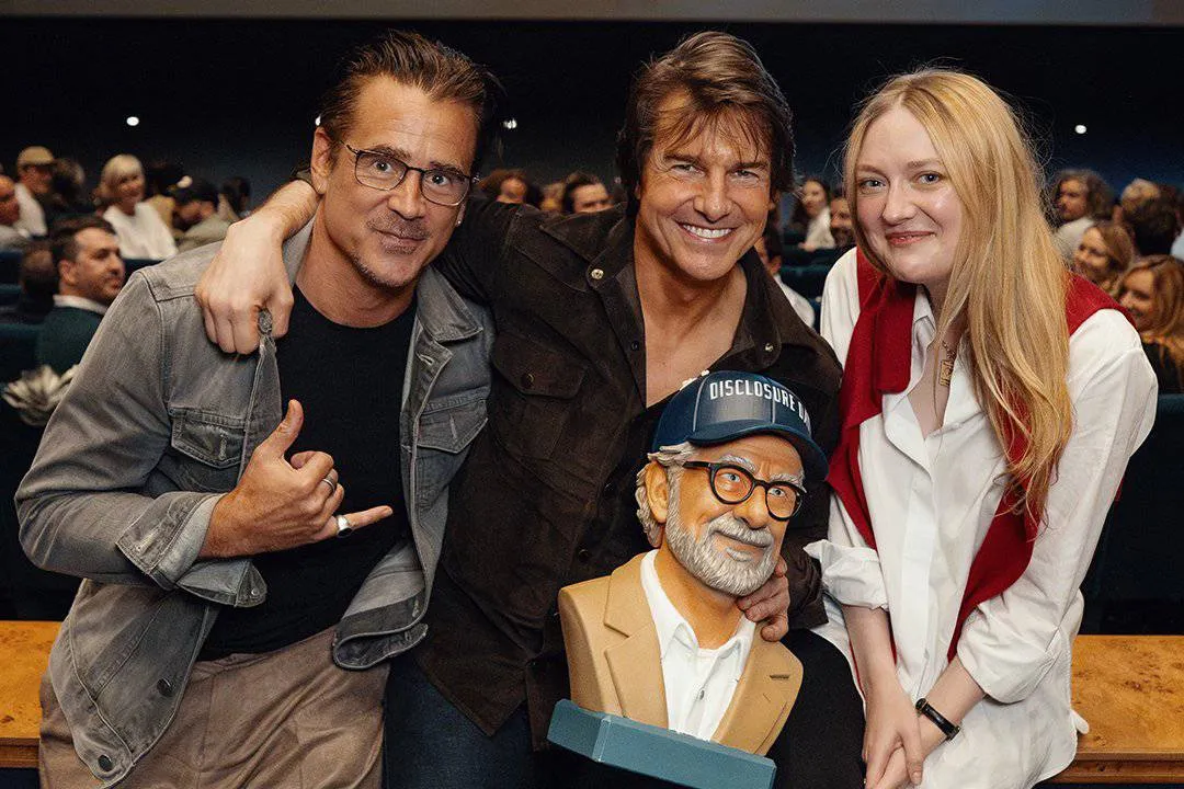 Tom Cruise, Colin Farrell, and Dakota Fanning smiling at a "Disclosure Day" event, with a fun Steven Spielberg head-shaped popcorn bucket visible.