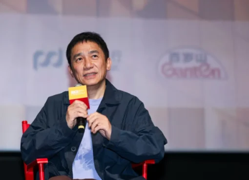 Tony Leung Chiu-wai smiling and speaking at a film festival event in Shanghai.