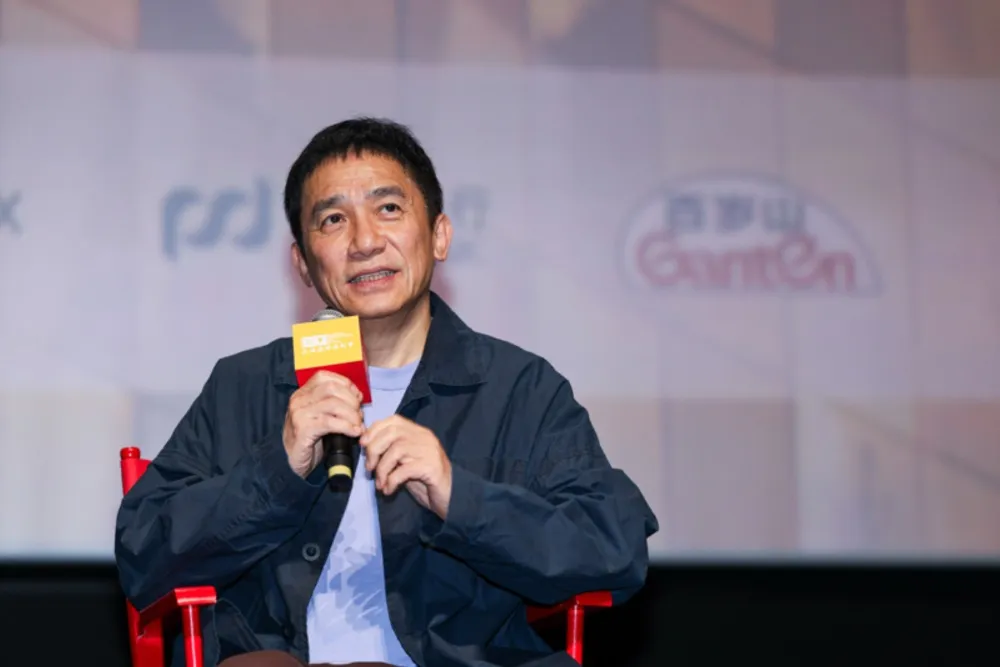 Tony Leung Chiu-wai smiling and speaking at a film festival event in Shanghai.