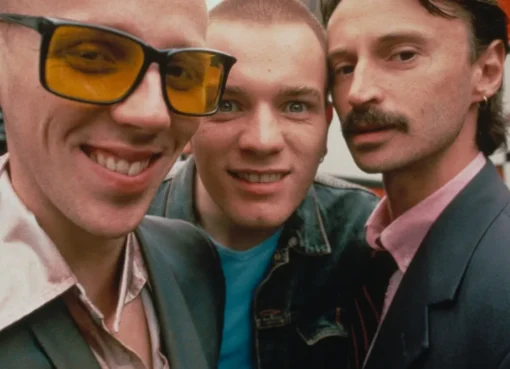 A still from the film Trainspotting showing the main cast, possibly Ewan McGregor and Jonny Lee Miller, in a distinctive, gritty urban setting.