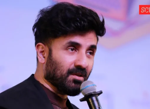 Vir Das on stage with a microphone, looking thoughtful and engaging with the audience.