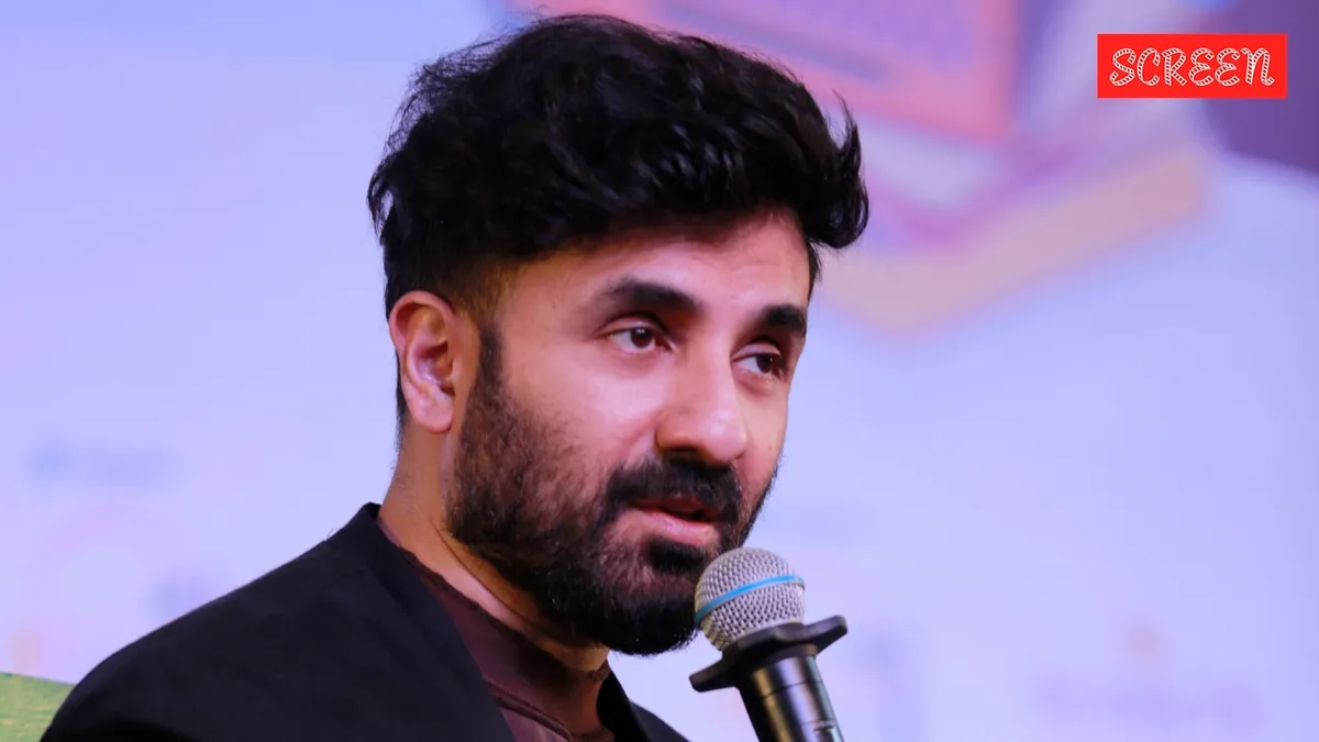 Vir Das on stage with a microphone, looking thoughtful and engaging with the audience.