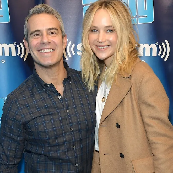 Jennifer Lawrence looking thoughtful, perhaps in a playful detective pose, next to a smiling Andy Cohen.