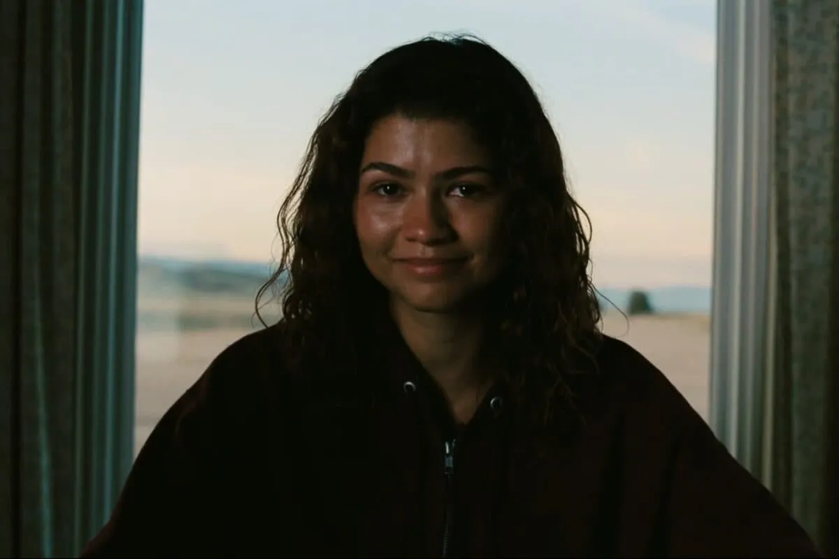 Zendaya looking emotional in a scene with neon lighting
