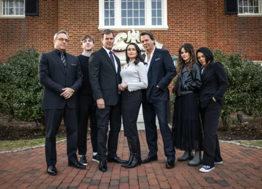 A dark and mysterious promotional image for 'Death on the Brandywine,' featuring the cast members looking thoughtful and slightly tense against a shadowy background.