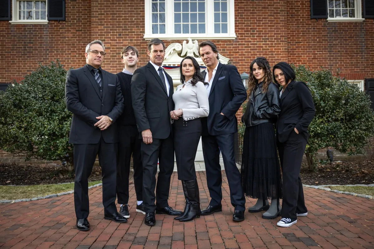 A dark and mysterious promotional image for 'Death on the Brandywine,' featuring the cast members looking thoughtful and slightly tense against a shadowy background.