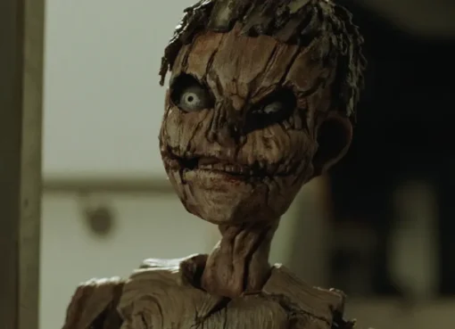 A gruesome, flesh-covered Pinocchio puppet with a sinister expression, part of the new horror universe.