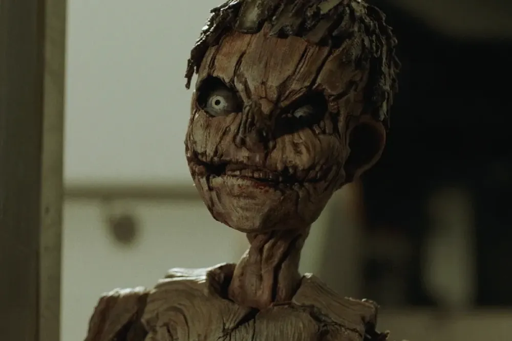 A gruesome, flesh-covered Pinocchio puppet with a sinister expression, part of the new horror universe.