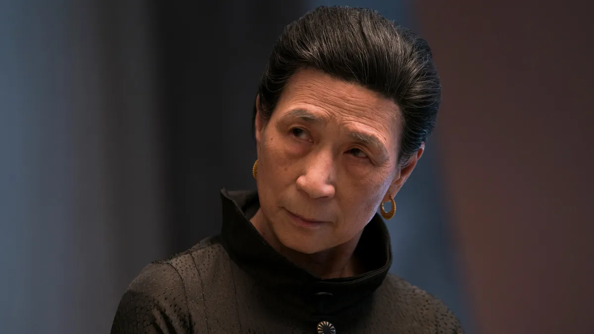 Wai Ching Ho in character as Madame Gao, looking calm and serious with a subtle smirk.