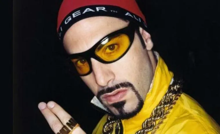 Sacha Baron Cohen as Ali G with his signature yellow tracksuit and sunglasses.
