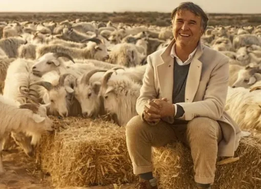 Image of Brunello Cucinelli in a stylish, high-quality suit, possibly against an Italian countryside backdrop.