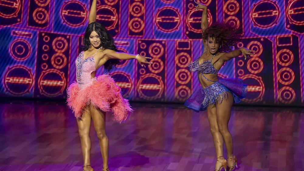 A diverse group of dancers in dazzling costumes performing a routine.