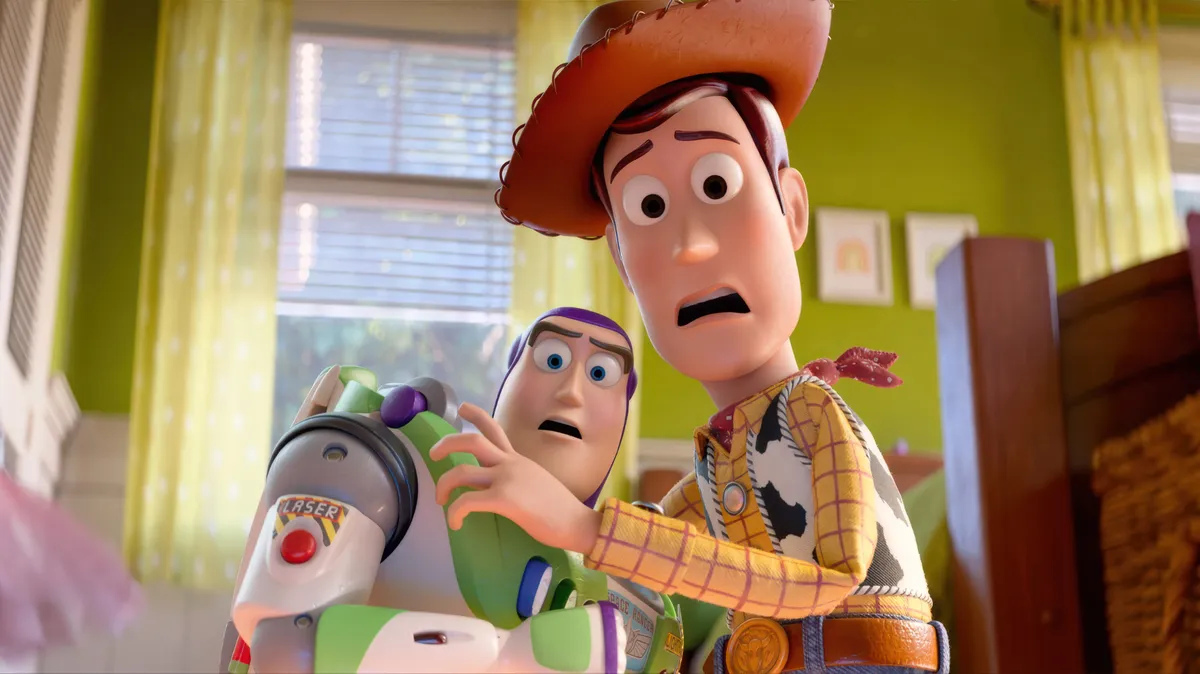 Woody and Buzz Lightyear smiling with other Toy Story characters in a celebratory pose.