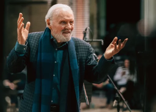 Anthony Hopkins looking thoughtful, possibly in a recording studio or with sheet music, with a serious but reflective expression.
