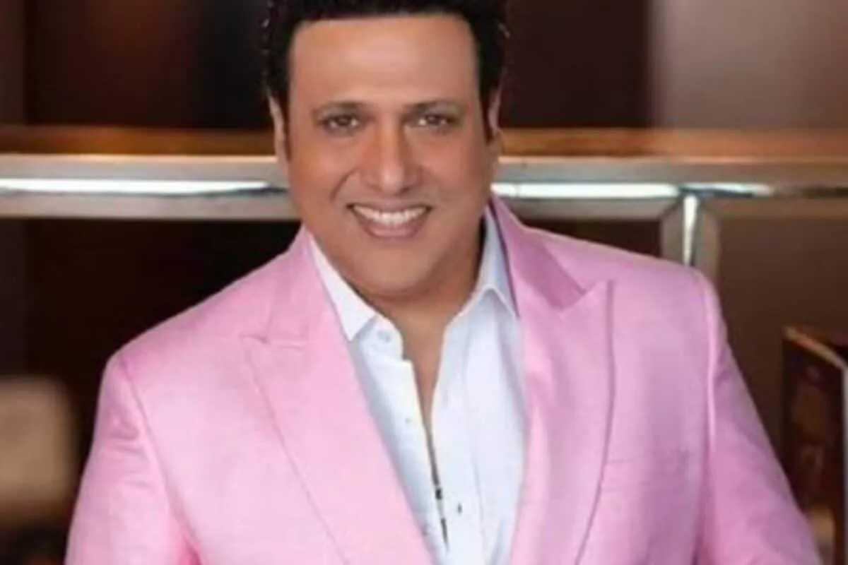 Actor Govinda smiling, gesturing excitedly with a vibrant background.
