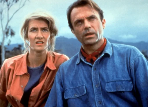 Laura Dern and Sam Neill smiling together on set of Jurassic Park.
