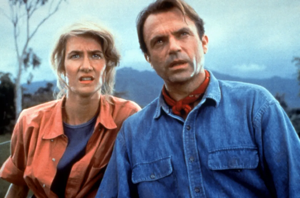 Laura Dern and Sam Neill smiling together on set of Jurassic Park.
