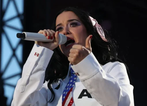 Katy Perry performing on stage with fireworks in the background.