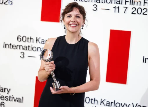 Maggie Gyllenhaal smiling at the Karlovy Vary Film Festival, holding an award.