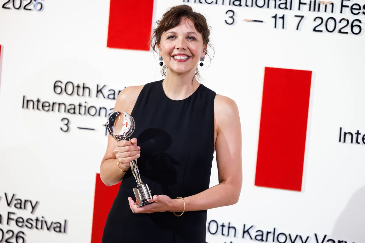 Maggie Gyllenhaal smiling at the Karlovy Vary Film Festival, holding an award.