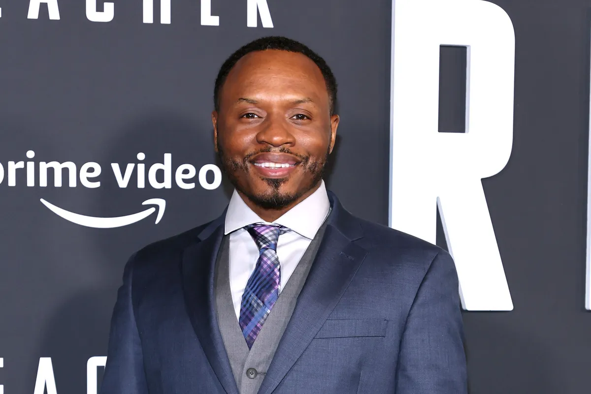 Malcolm Goodwin smiling at the camera, looking sharp.