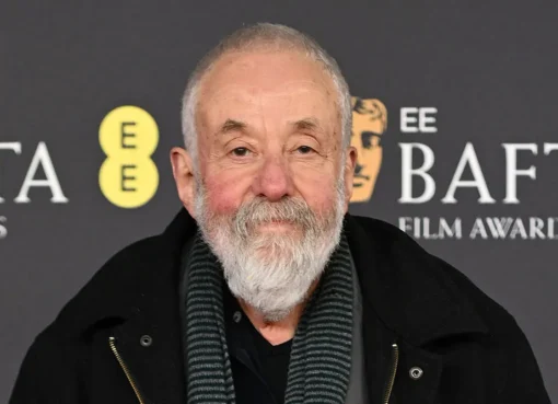 A photo of director Mike Leigh, an older man with glasses, smiling softly.