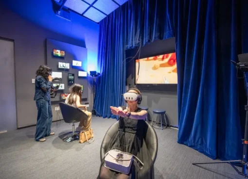 People experiencing immersive digital art in a dark room with glowing visuals.
