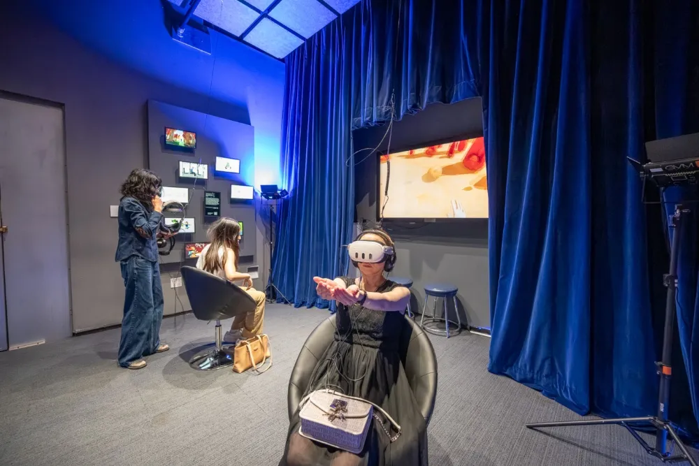 People experiencing immersive digital art in a dark room with glowing visuals.