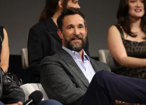 Noah Wyle smiling in a suit.