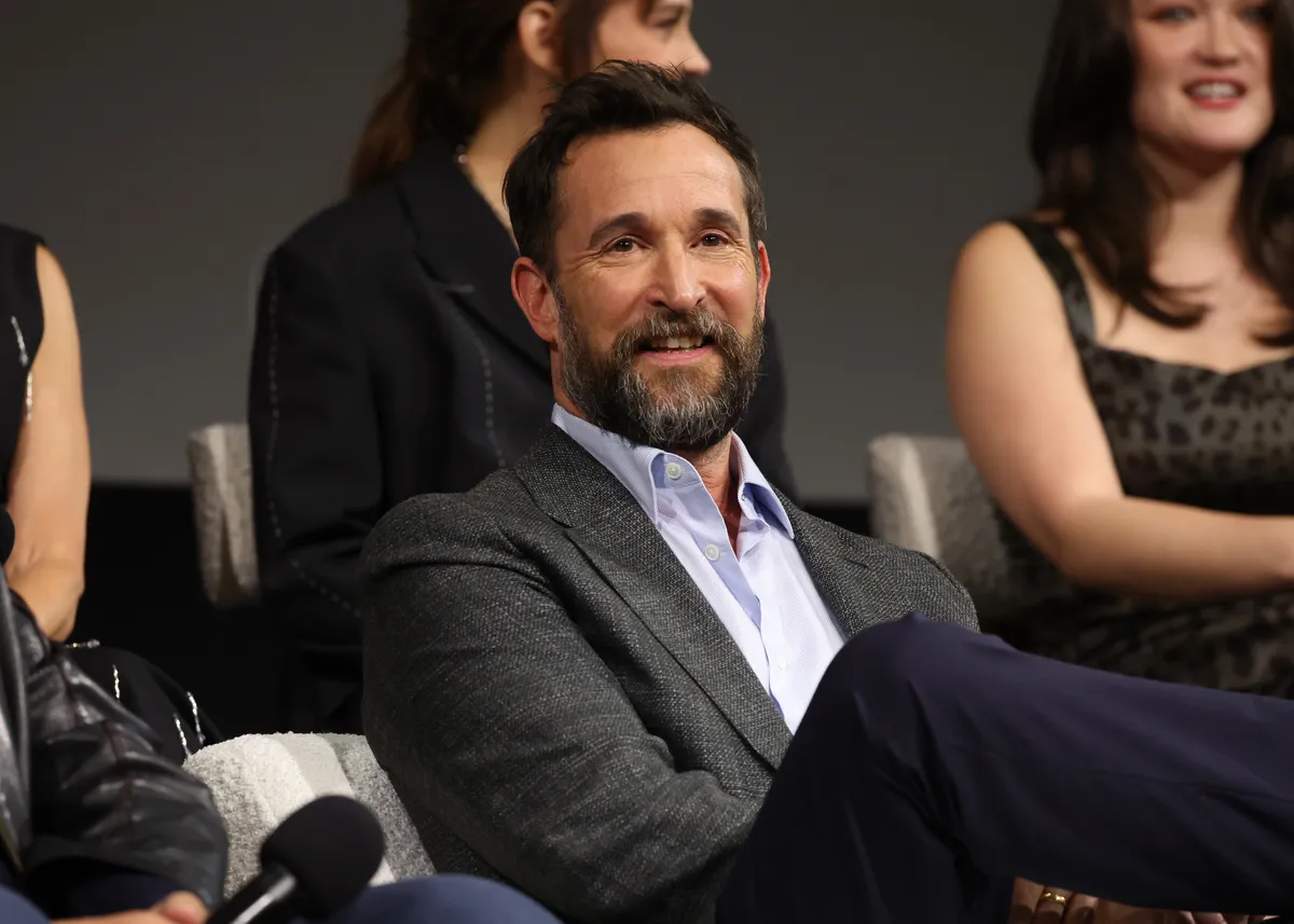 Noah Wyle smiling in a suit.
