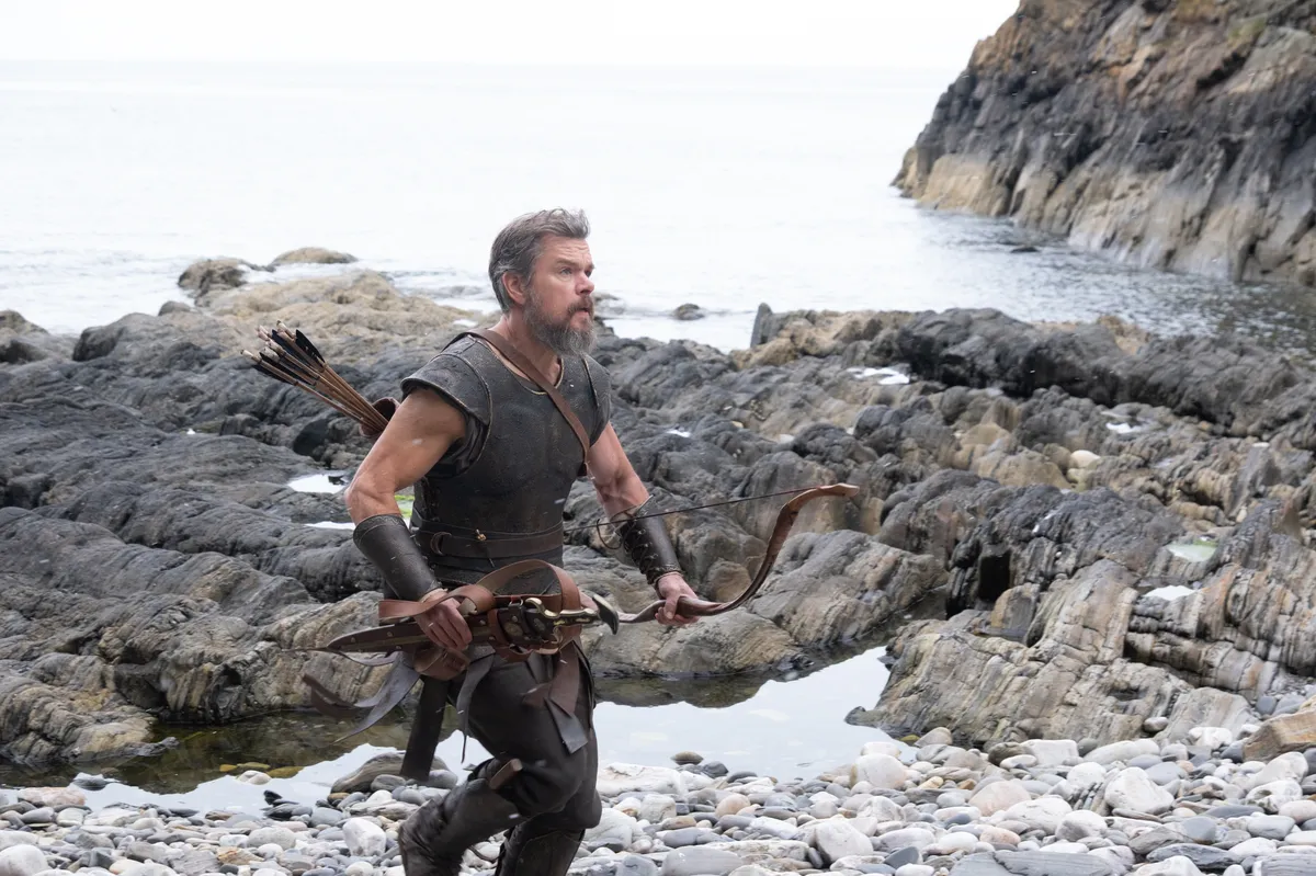 A dramatic shot from Christopher Nolan's 'The Odyssey' showing Matt Damon as Odysseus on a stormy sea.