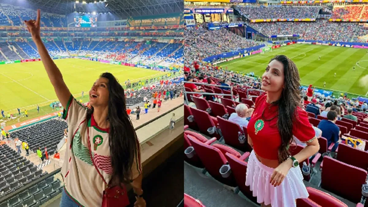 Nora Fatehi smiling at a football event with a microphone in front of a stadium crowd.