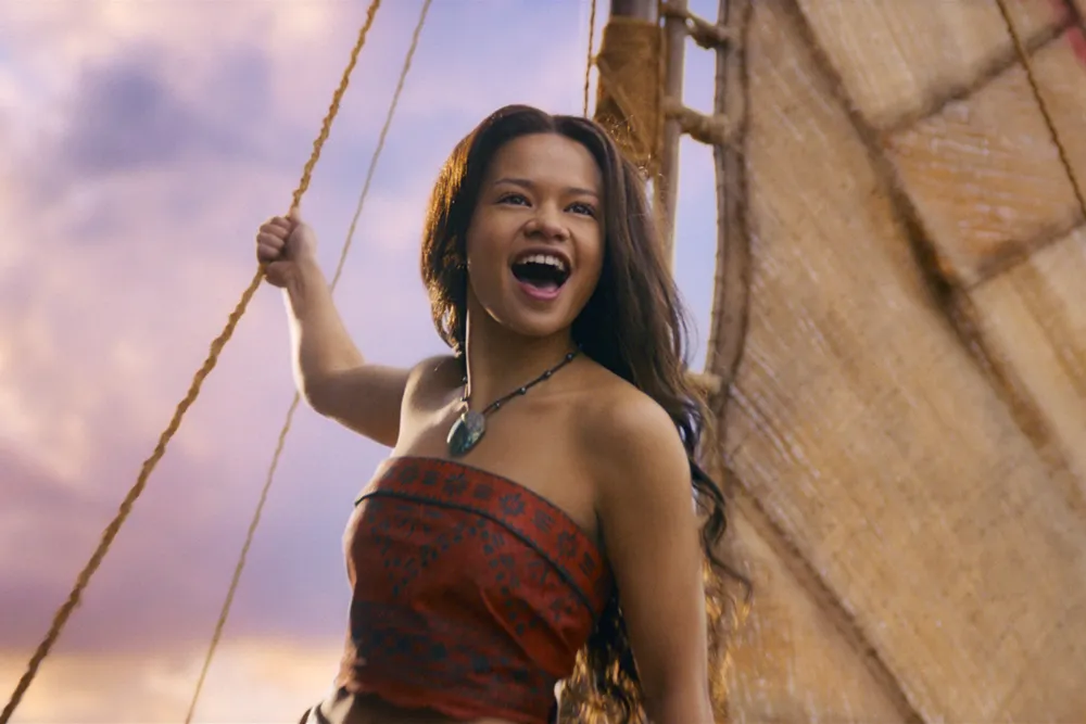 A vibrant image of Moana in a live-action setting, perhaps on a boat or by the ocean, with a determined expression.