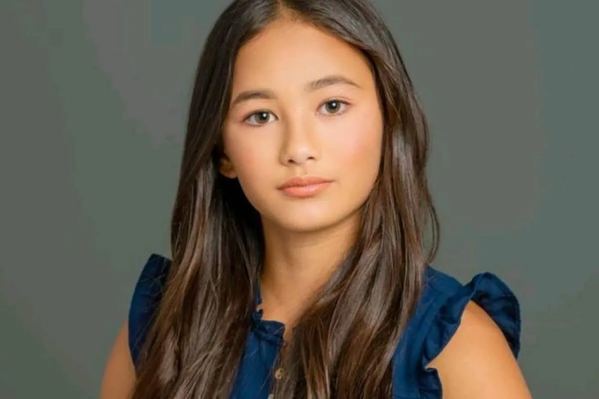A young girl with dark hair looking up.