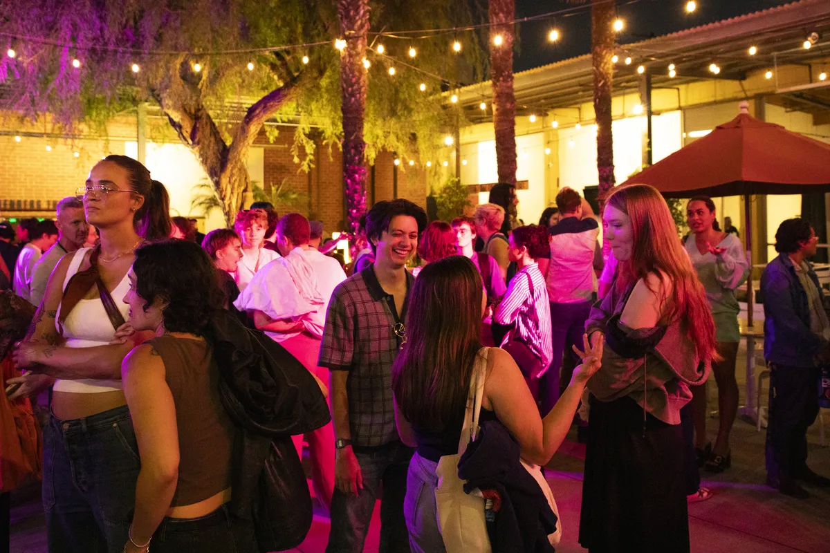 A vibrant image showing people gathered outside the Los Angeles LGBT Center's Renberg Theatre, with colorful film posters visible for Outfest.
