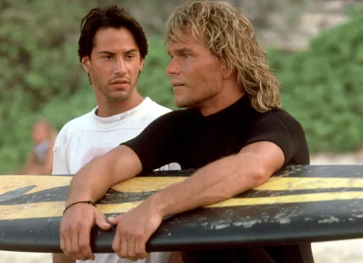 Keanu Reeves and Patrick Swayze riding a wave with surfboards in the movie Point Break.