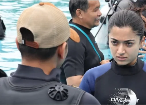 Rashmika Mandanna stands in a pool with her back to the camera, water up to her knees, creating a dramatic silhouette.