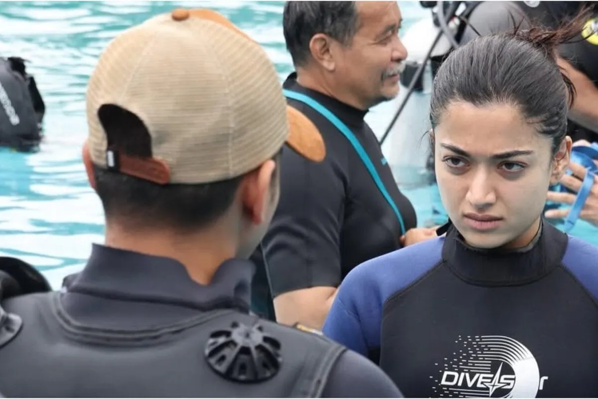 Rashmika Mandanna stands in a pool with her back to the camera, water up to her knees, creating a dramatic silhouette.