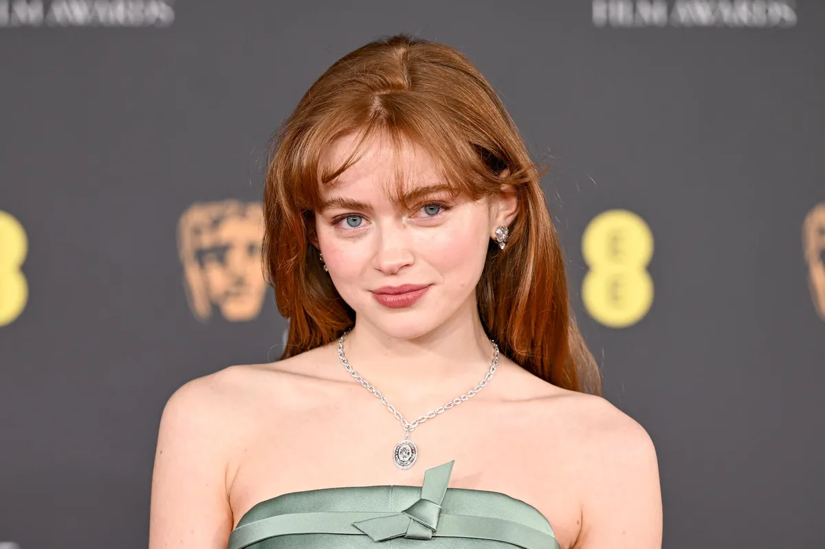 Sadie Sink as Felicia Hardy, the Black Cat, in a black leather suit looking mischievous and confident.